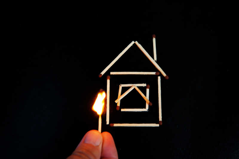 黑色背景下用一根火柴点燃火柴拼成的房子模型