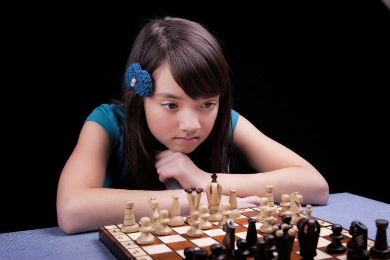 对着国际象棋深思的年轻女孩