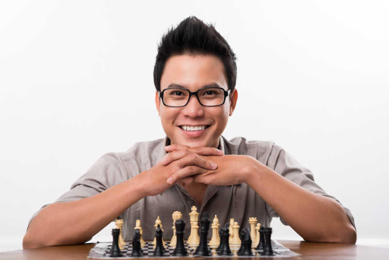 在国际象棋棋盘前微笑的棋手