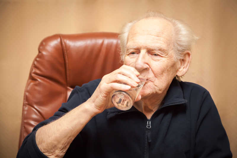 拿着杯子喝水的老人