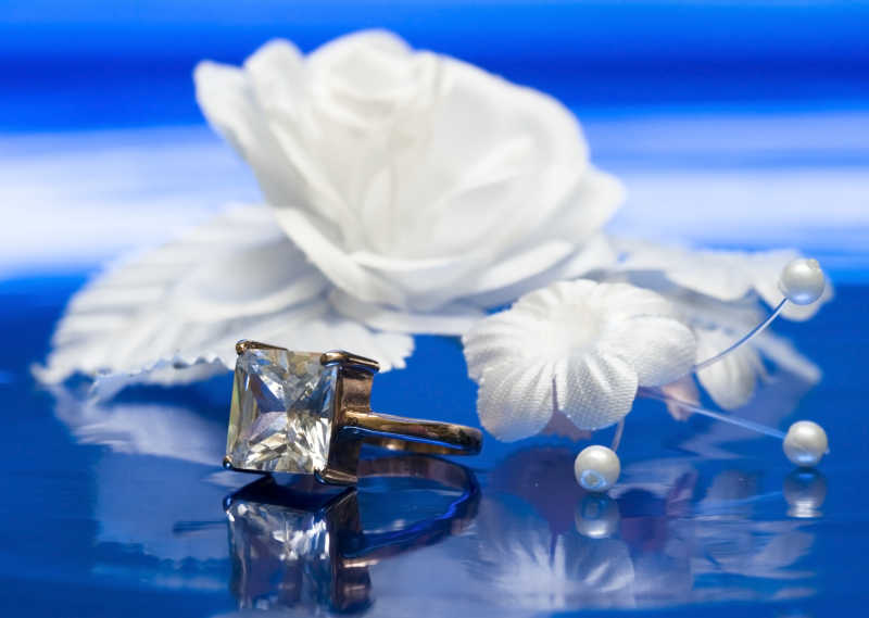 蓝色背景上的白色花朵和钻石戒指