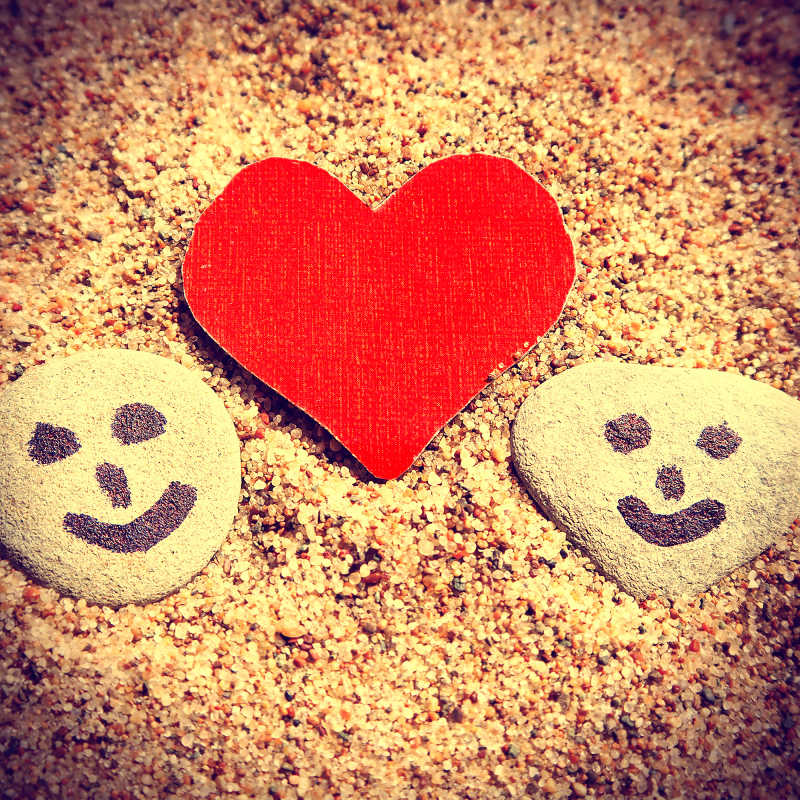 沙滩上的爱心和画着笑脸的石头