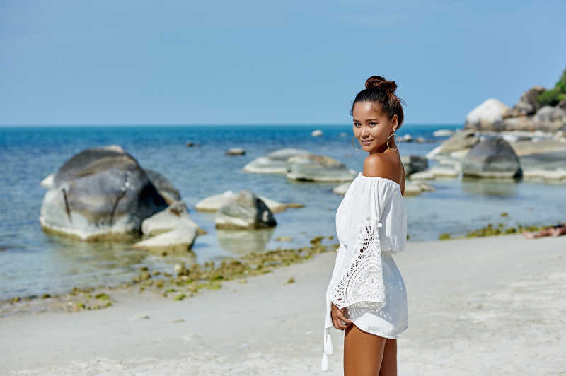 大海边白色沙滩上穿着白色连衣裙的女孩