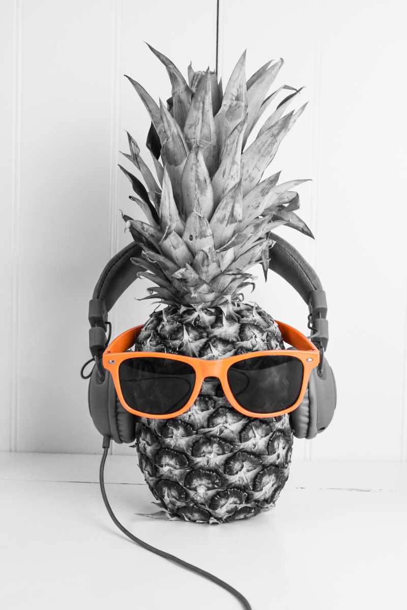 灰色背景下带着耳机和眼镜的菠萝