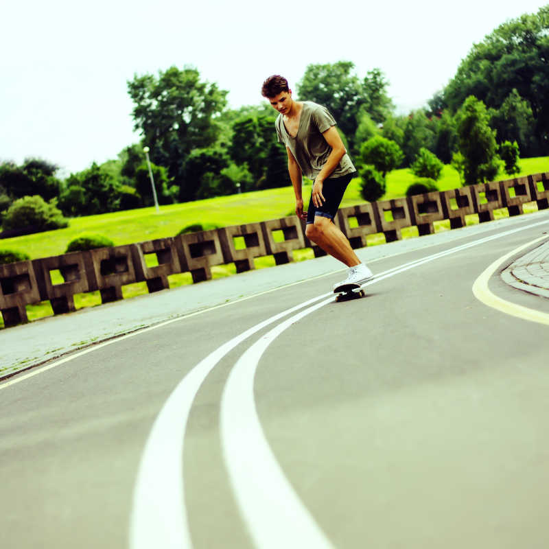 公路上玩滑板的年轻小伙
