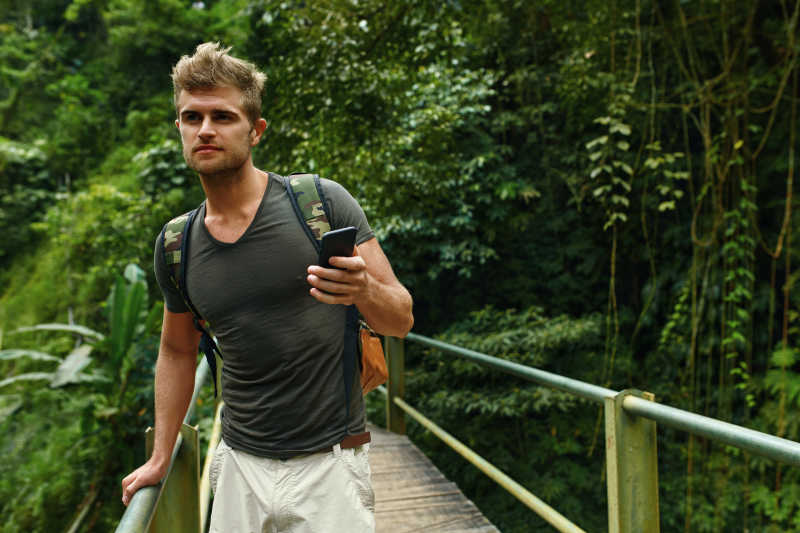 男性在夏季旅游度假时手持智能手机