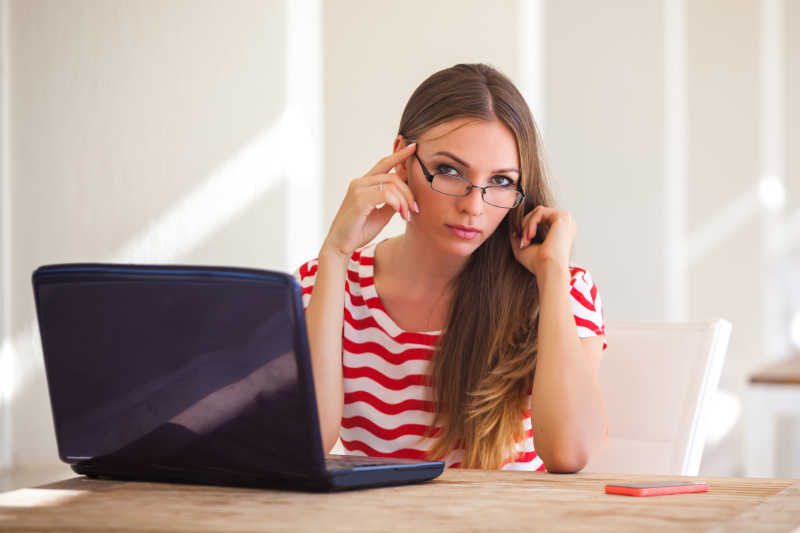带着眼镜使用笔记本电脑的女人