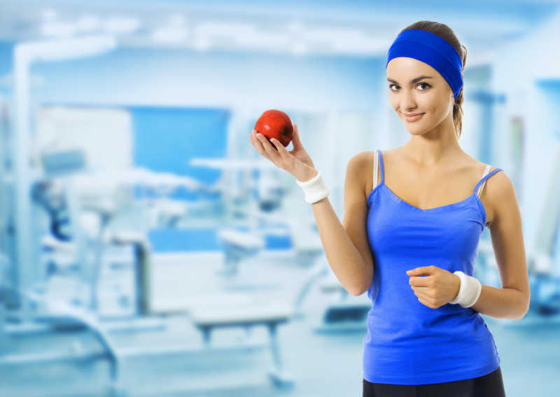 拿着红色苹果在健身房内的女人