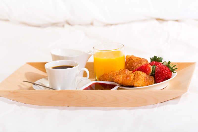 卧室白色的床上的咖啡和羊角面包和果汁的早餐