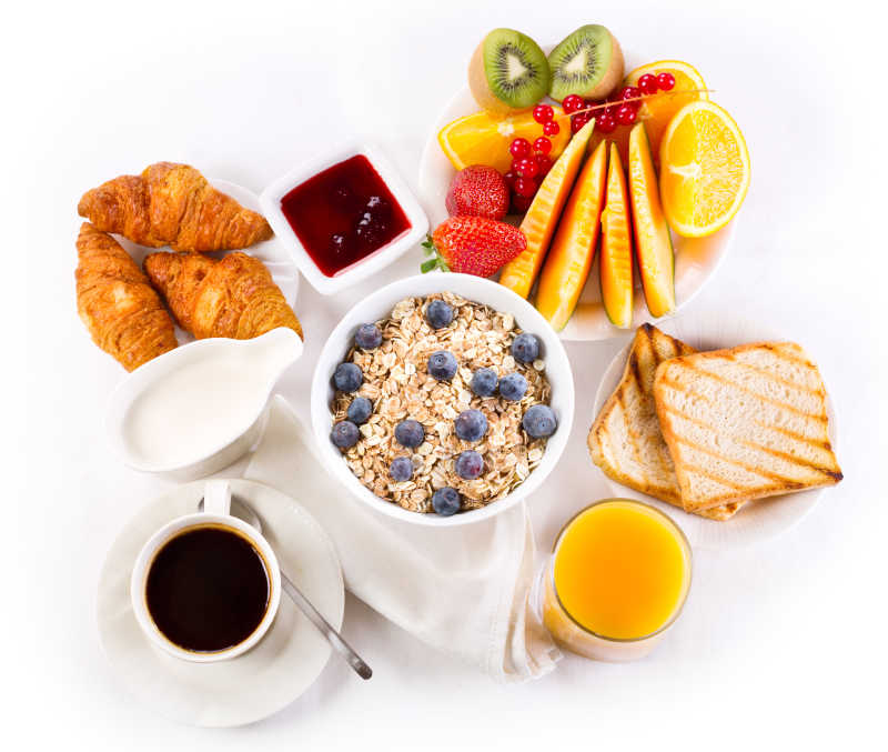 白色背景下健康的咖啡和羊角面包与果汁的早餐