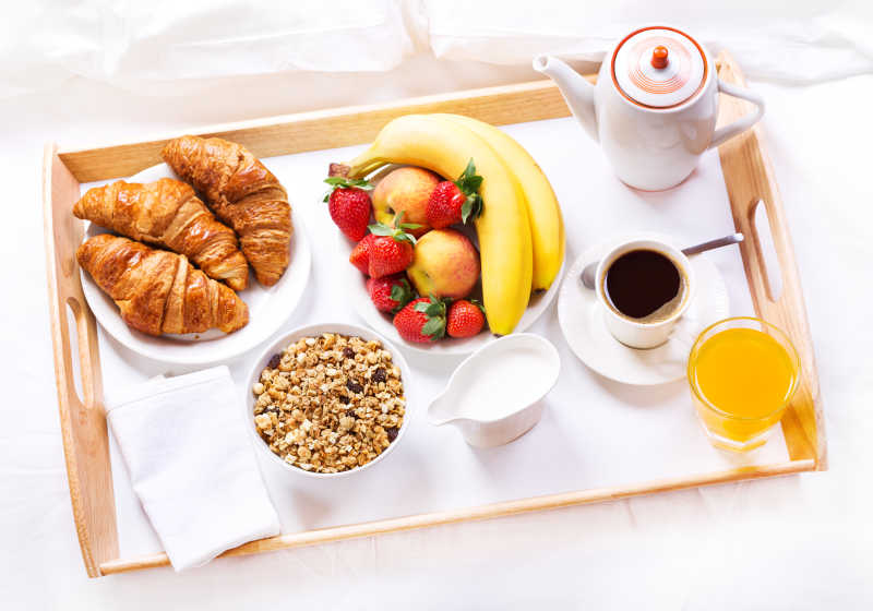 白色的床上的咖啡和面包与谷物的早餐
