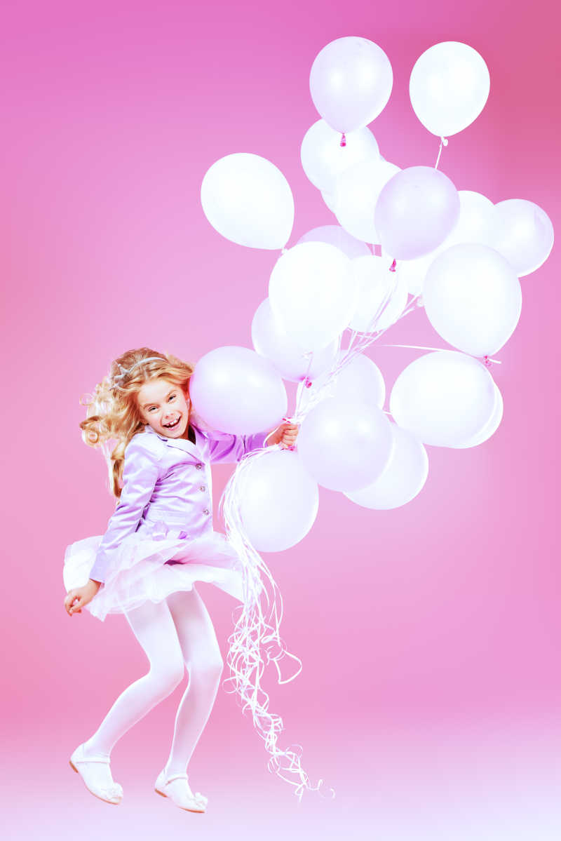 金发小女孩手里拿着一束粉色气球
