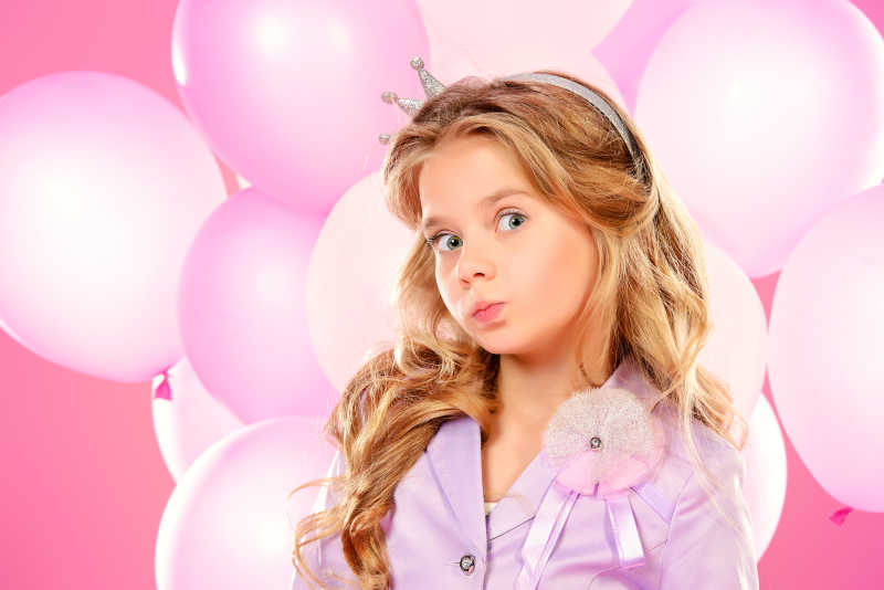 可爱的小女孩手里拿着一束粉色气球