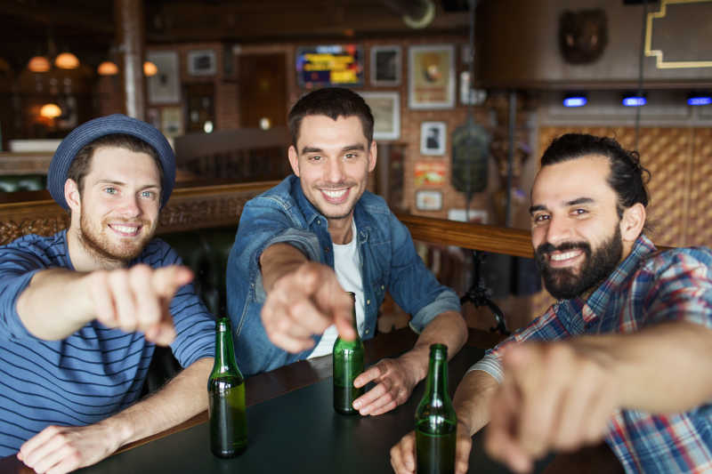 酒吧里喝酒的男人们一起举起手指