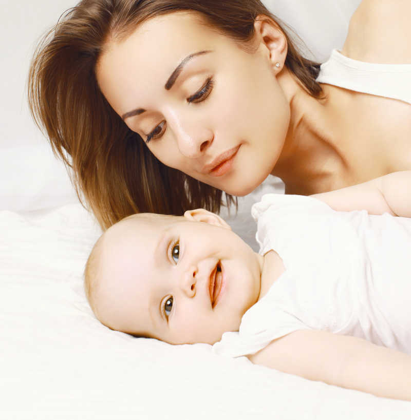 卧室大床上快乐的婴儿和母亲的特写