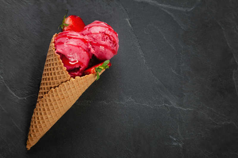 黑色背景上的草莓粉色冰淇淋蛋筒