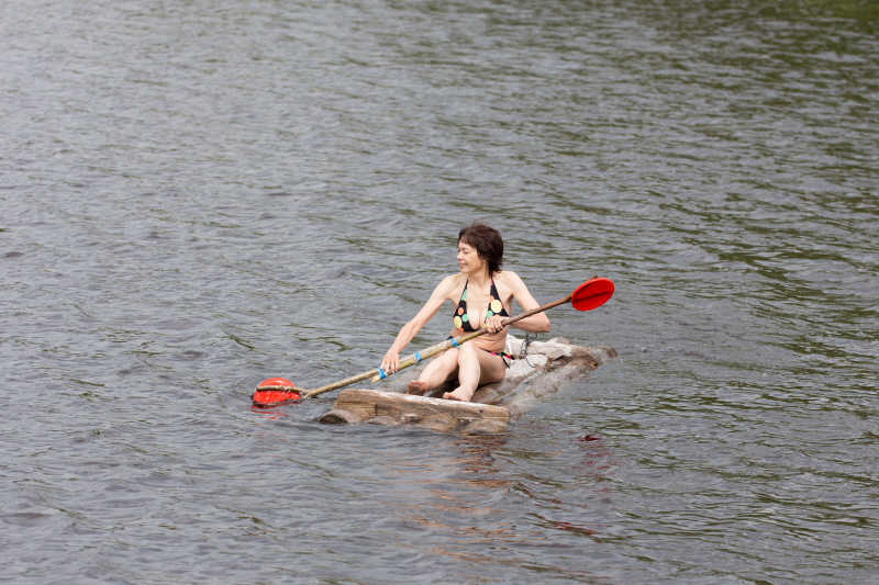 湖面上漂浮木筏上划水的女人
