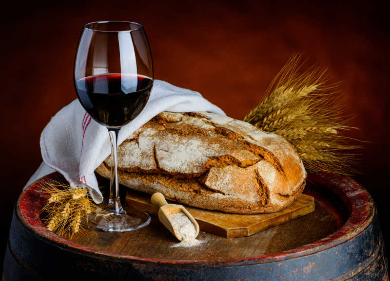 木桶上的红酒酒杯和小麦面包