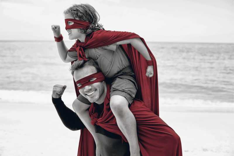 开心的父子俩穿着英雄服饰站在海边