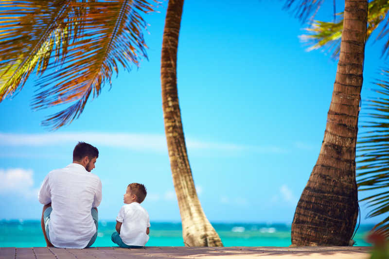 快乐的父亲和儿子坐在海边