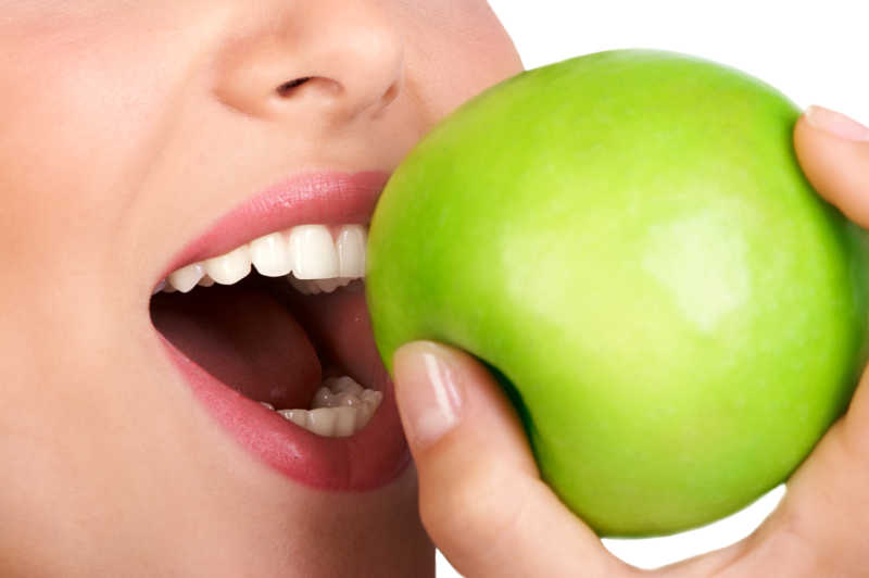 年轻女人吃着一个青苹果