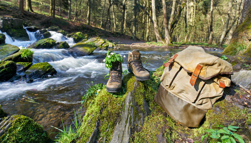 小溪边的登山鞋与旅行包