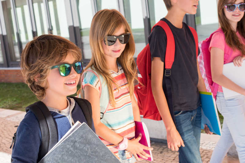 行走在校园中背着书包带着太阳眼镜的四个学生