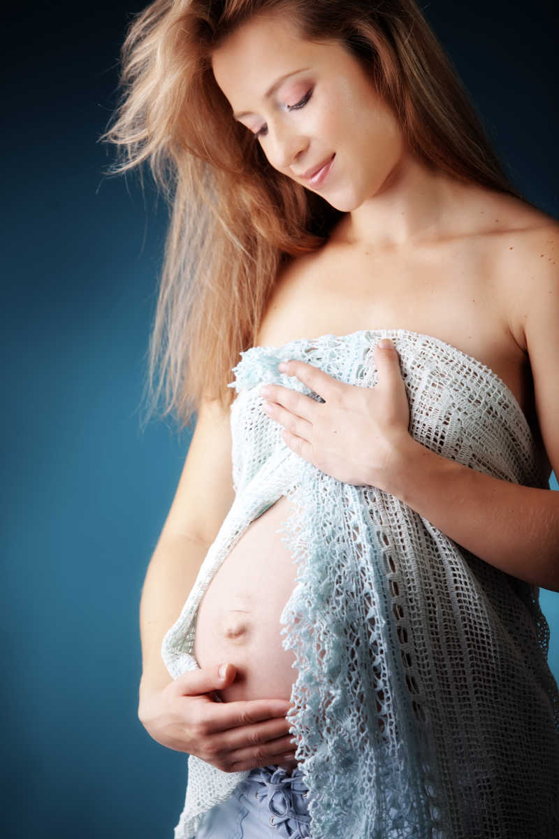 深蓝色背景下围着蕾丝衣服的孕妇
