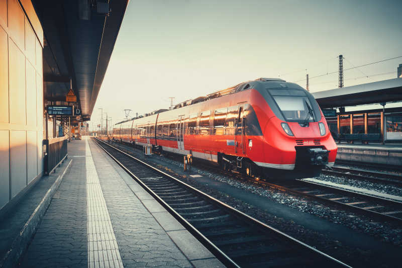 美丽的火车站与现代红色通勤列车在多彩的夕阳在纽伦堡