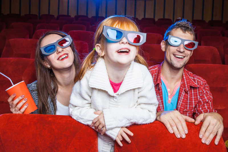 坐在电影院里看电影的快乐家庭