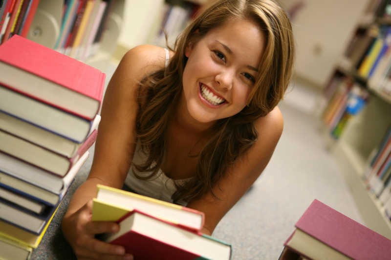 图书馆里拿着书本的年轻女孩
