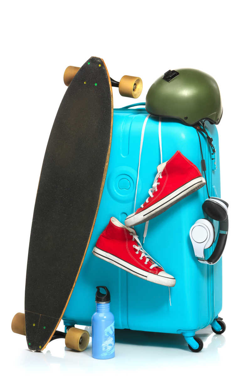 白色背景下的滑板运动鞋水壶和蓝色旅行箱