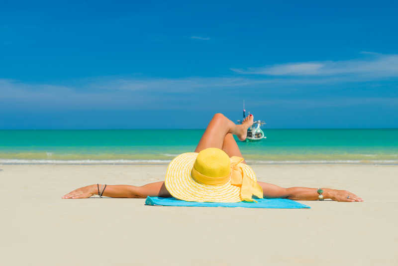 躺在沙滩上戴着太阳帽晒日光浴的美女