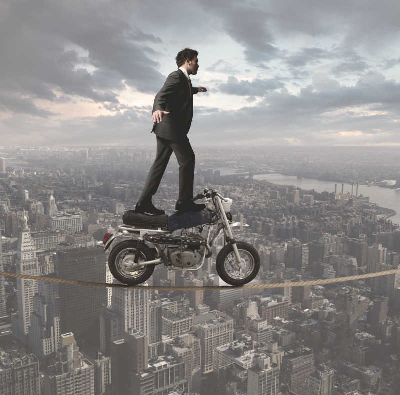高空绳索站在摩托车上保持平衡的男子