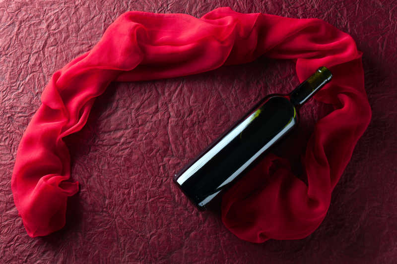 红色纹理背景上的红酒和红纱