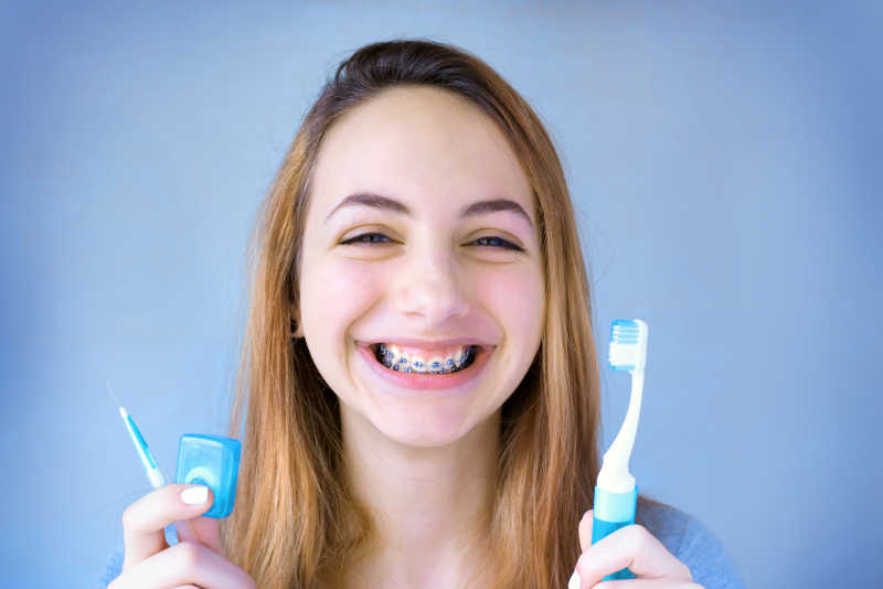 微笑的女孩带着牙套拿着牙刷