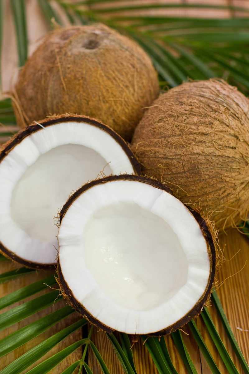 绿叶上成熟的椰子和打开露着白色椰肉的椰子