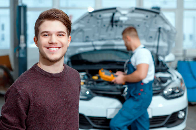 汽车修理厂里的汽车修理工和微笑的顾客