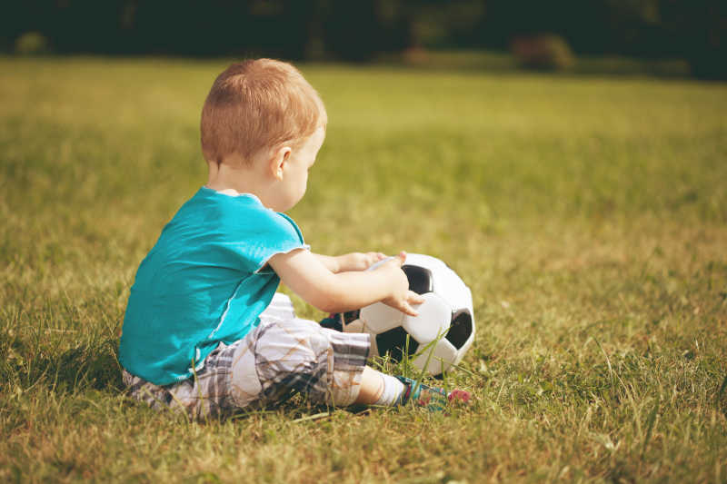 草地上玩足球的可爱的小男孩