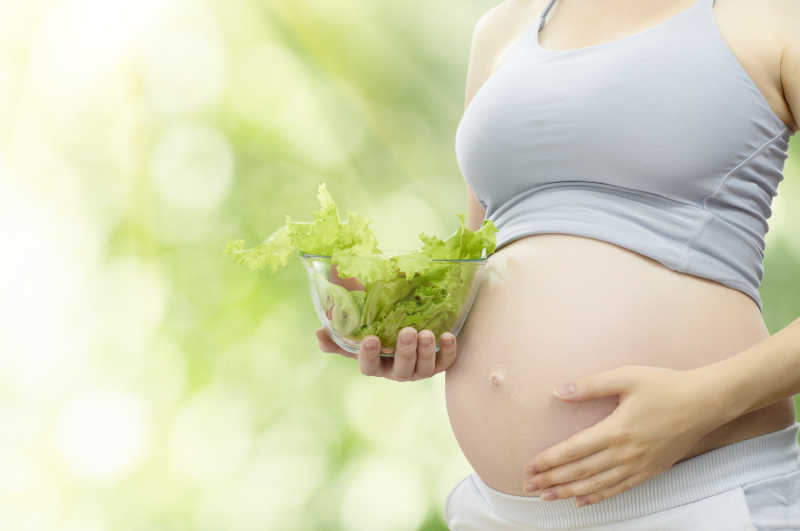 吃健康蔬菜的年轻孕妇