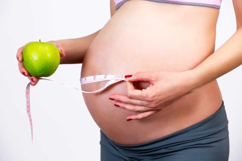 测量肚子大小的年轻孕妇