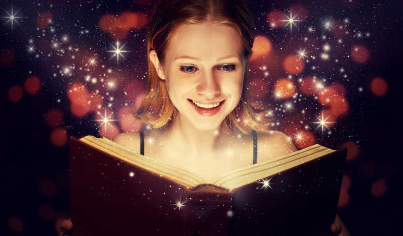 女孩看着发光的魔法书