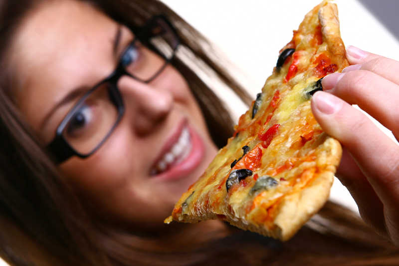 戴眼镜的年轻女人吃披萨