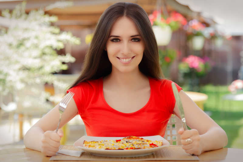 美女拿着刀叉准备吃披萨
