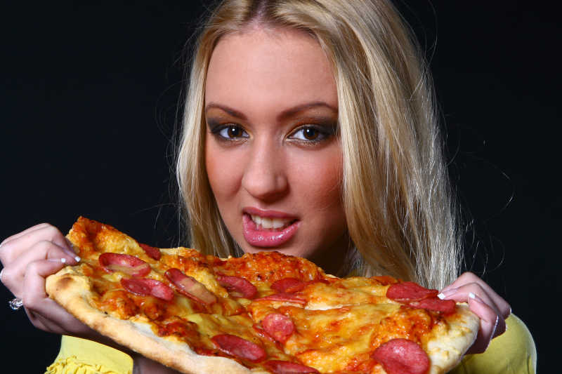 漂亮的年轻女人吃披萨