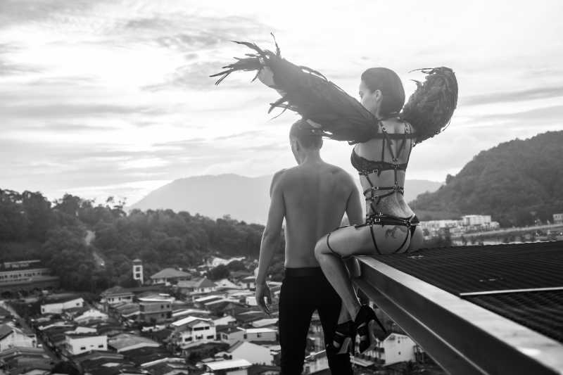 赤裸的男人和性感的天使女人站在屋顶上