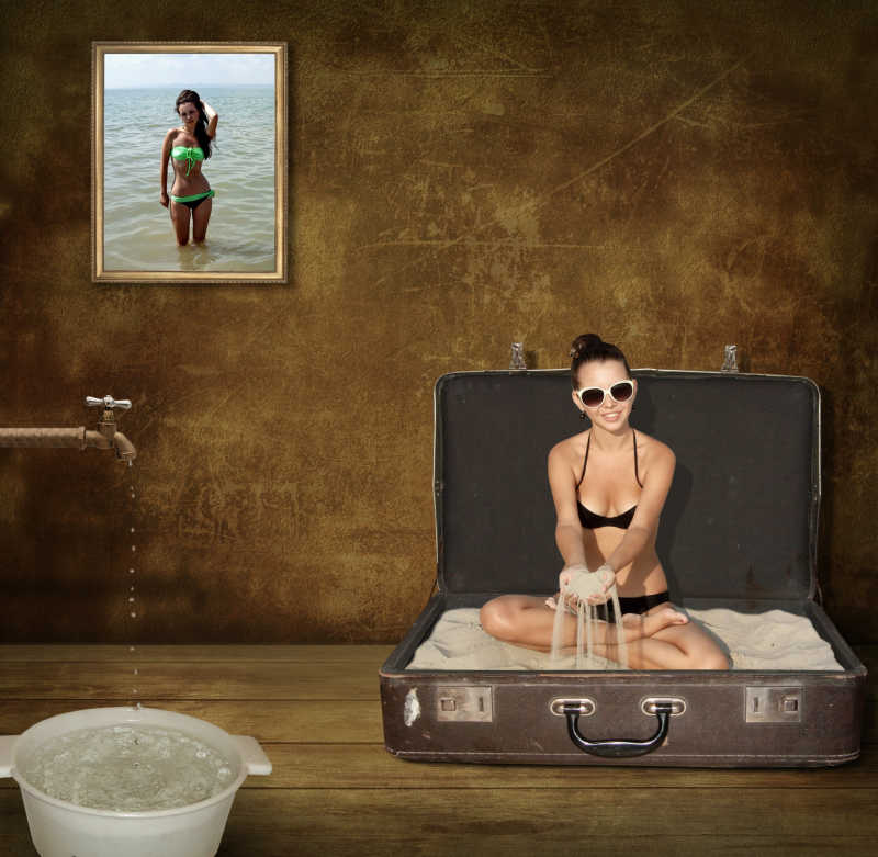 一个女孩坐在一个装有海砂的行李箱里