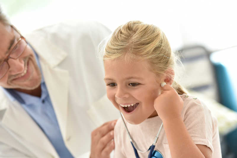 戴着听诊器微笑的小女孩和医生