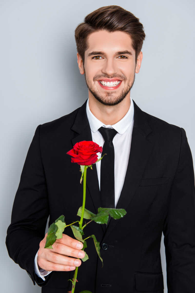 英俊的商人微笑着捧着红玫瑰