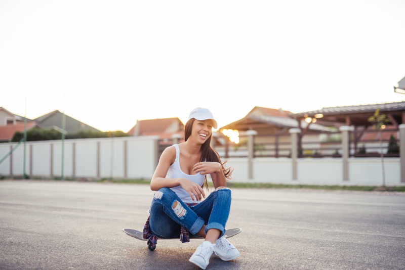 街上一个年轻女孩坐在滑板上